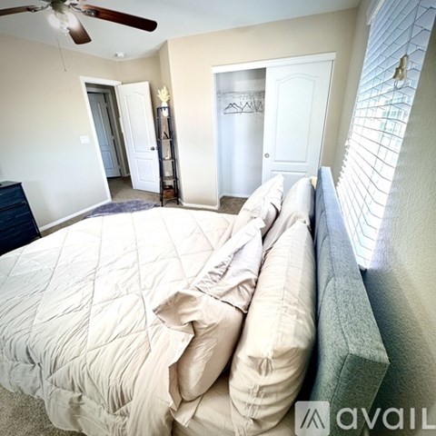 A bedroom with a large bed and a ceiling fan.