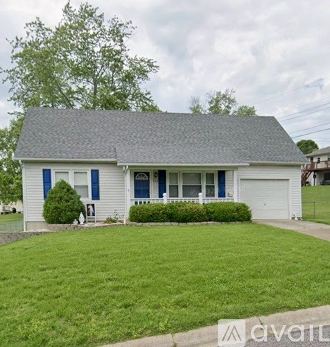 A white house with a grey roof and blue trim.