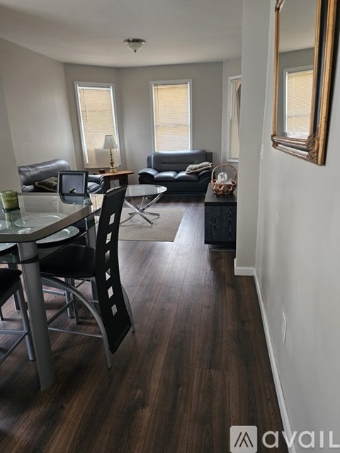 A living room with a black couch and a glass table with chairs.