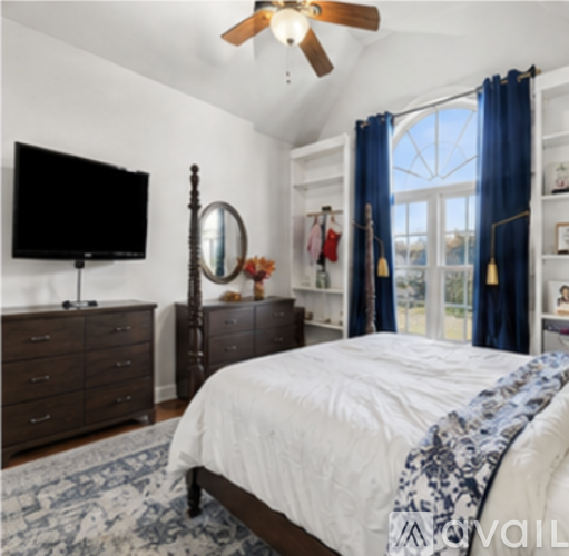 A bedroom with a bed, dresser, mirror, and a television.