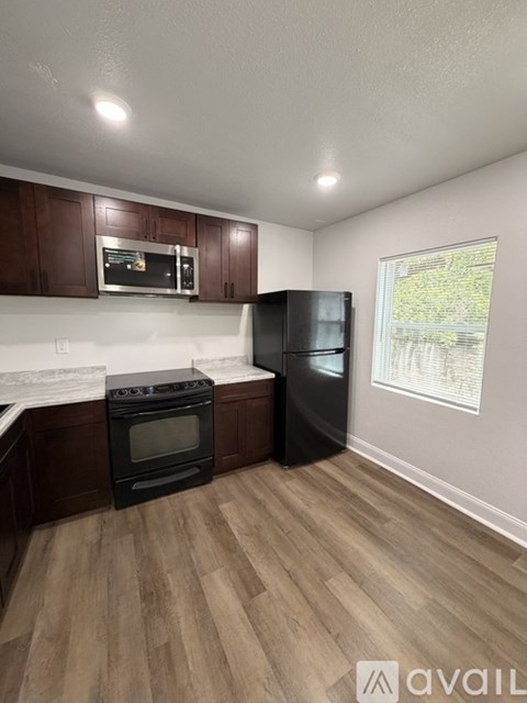 A kitchen with dark wood cabinets and a black refrigerator.