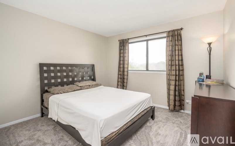 A bedroom with a large bed and a window with curtains.