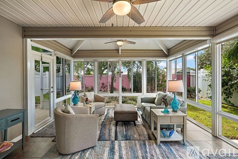 A sunroom with a ceiling fan and furniture.