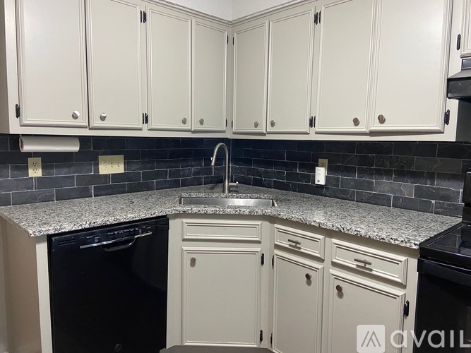 A kitchen with white cabinets and a granite countertop.