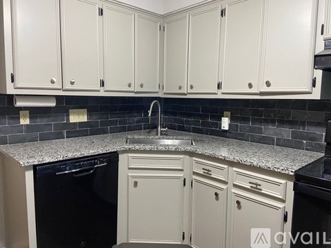A kitchen with white cabinets and a granite countertop.
