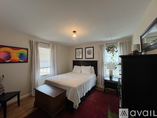 A bedroom with a large bed and a painting on the wall.
