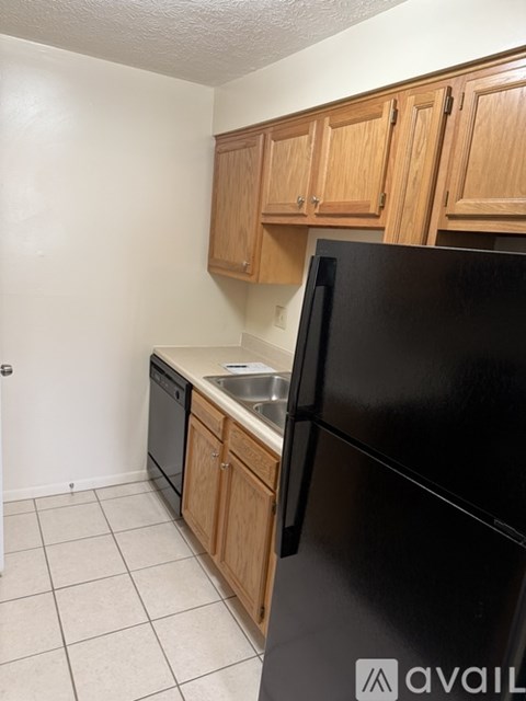 A kitchen with wooden cabinets and a black refrigerator.