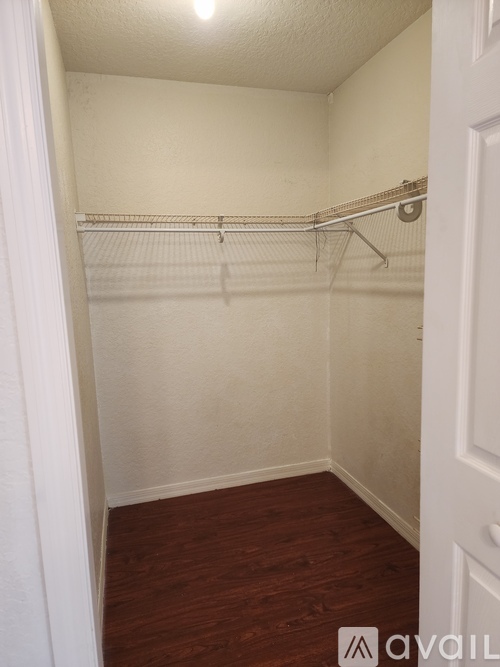 A small, empty room with a wooden floor and white walls.