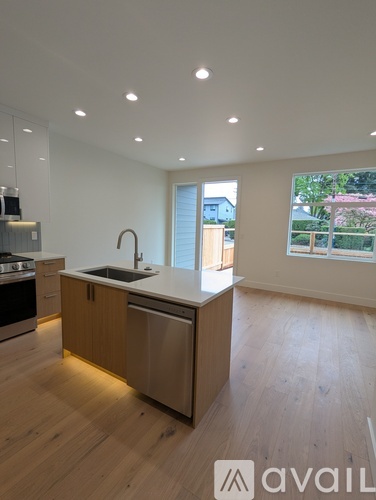 A room with wooden flooring and a window showing a view of a house and trees.