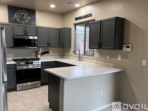 A kitchen with dark cabinets and a stainless steel refrigerator.
