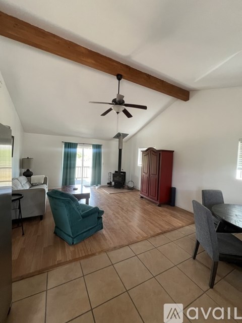 A living room with a green chair and a ceiling fan.