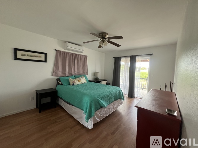 A bedroom with a bed, a ceiling fan, and a wooden floor.
