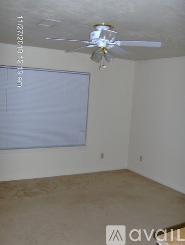 A room with a ceiling fan and a window with blinds.