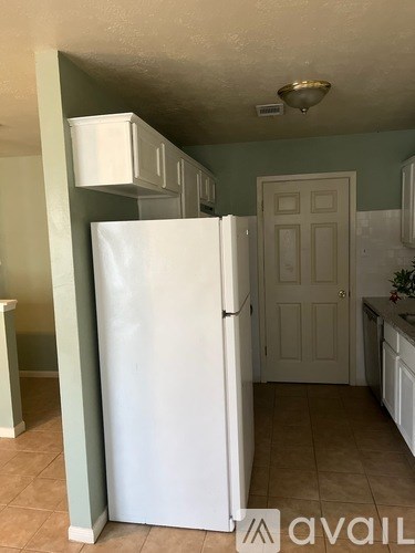A white refrigerator in a kitchen with green walls.