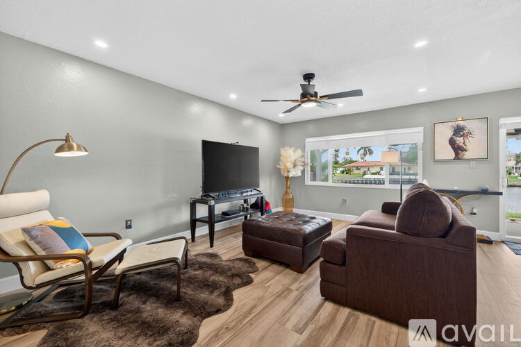 A living room with a brown couch, a chair, a table with a lamp, and a television.