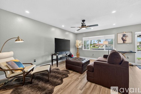 A living room with a brown couch, a chair, a table with a lamp, and a television.
