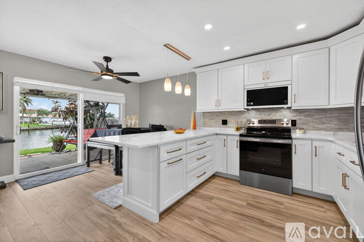 A modern kitchen with white cabinets and a black stove top oven.