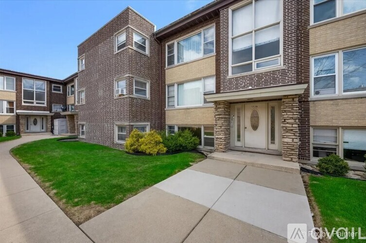 A brick apartment building with a green lawn in front.