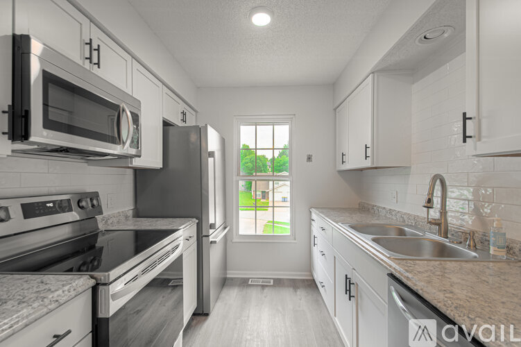 A kitchen with white cabinets and a black refrigerator.