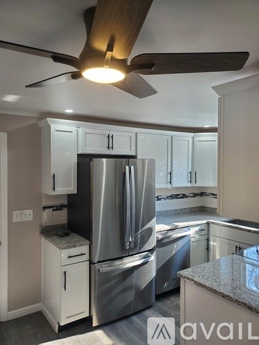 A kitchen with a stainless steel refrigerator and white cabinets.