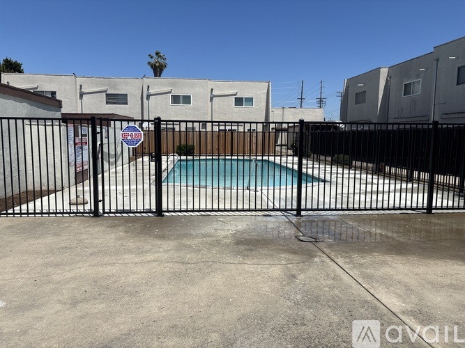 A pool surrounded by a black fence with a sign on it.