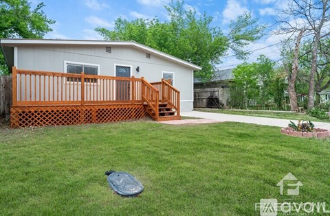 A small house with a wooden deck and a green lawn.