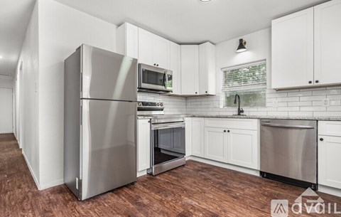 A kitchen with white cabinets and a wooden floor.