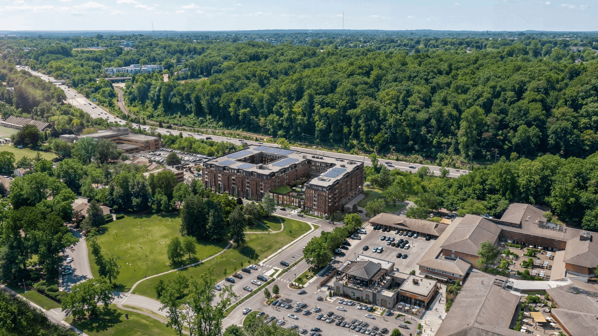 An aerial view of a large building complex surrounded by a parking lot and greenery.