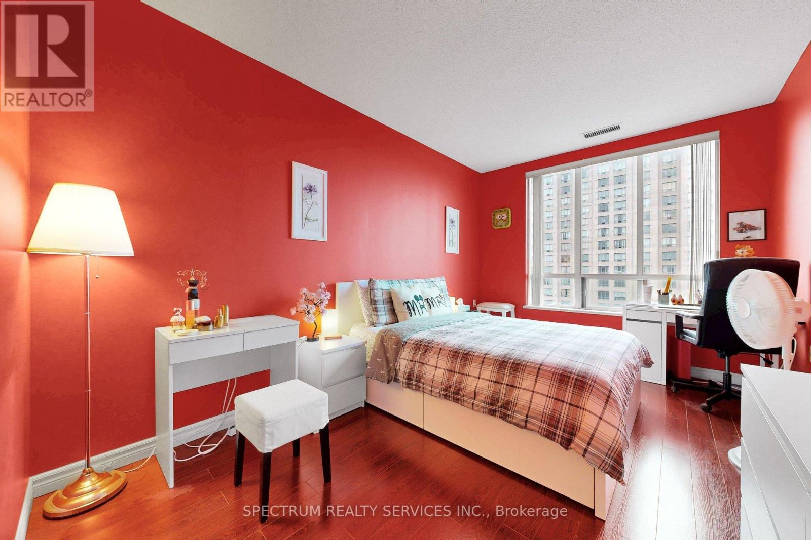 A bedroom with red walls and a bed with a plaid comforter.