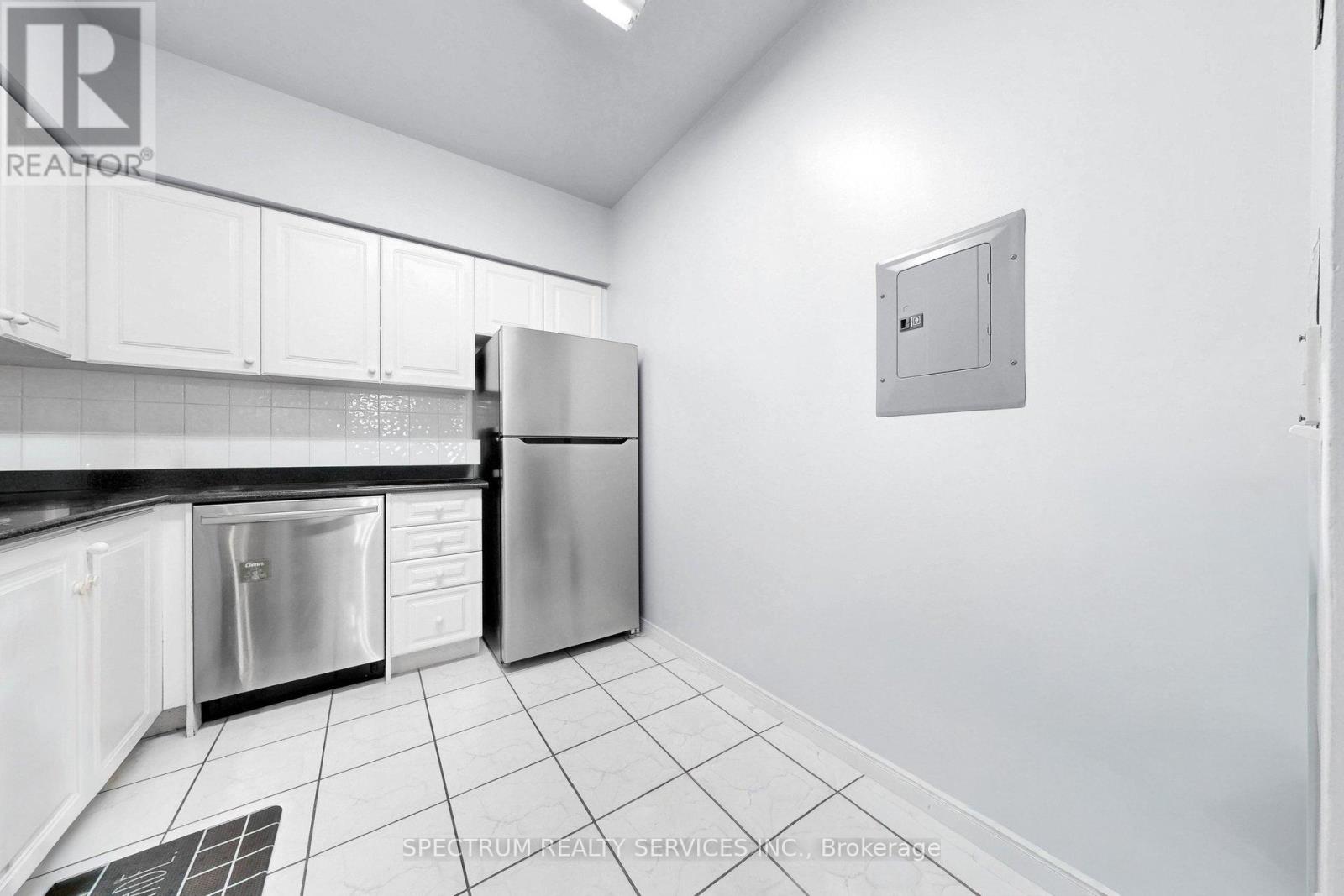 A kitchen with white cabinets and a stainless steel refrigerator.
