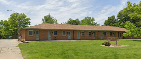 A small building with a brown roof and a green lawn in front.
