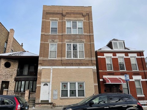 A black car is parked in front of a brick building.