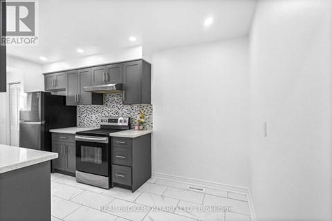 A modern kitchen with dark grey cabinets and white countertops.