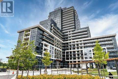 A modern multi-story building with a glass facade and a landscaped area in front.
