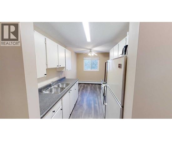 A kitchen with white cabinets and a refrigerator.
