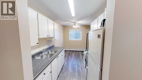 A kitchen with white cabinets and a refrigerator.