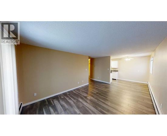 A spacious room with wooden flooring and a white ceiling.