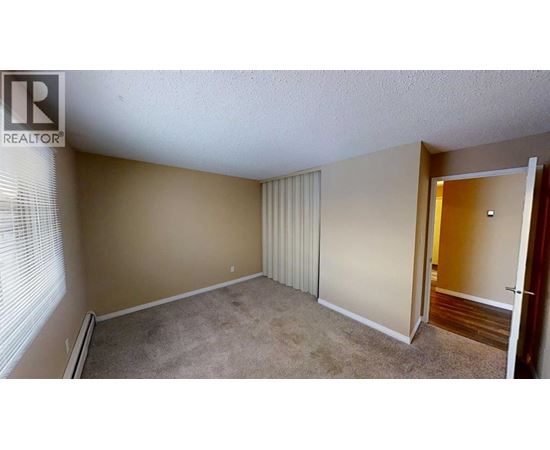 A room with a carpeted floor and a door leading to another room.