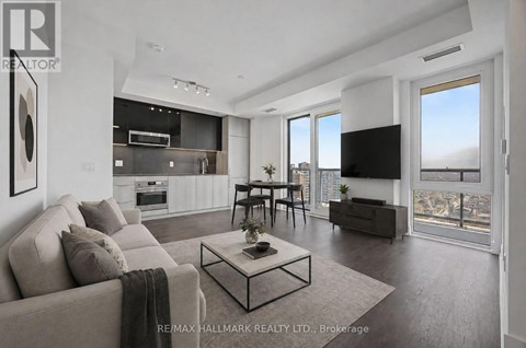 A modern living room with a large couch, a coffee table, and a flat-screen TV.