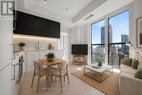 A modern kitchen with a dining table and chairs, a couch, and a view of the city.