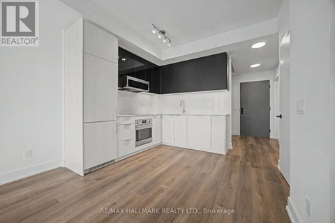 A kitchen with white cabinets and a wooden floor.