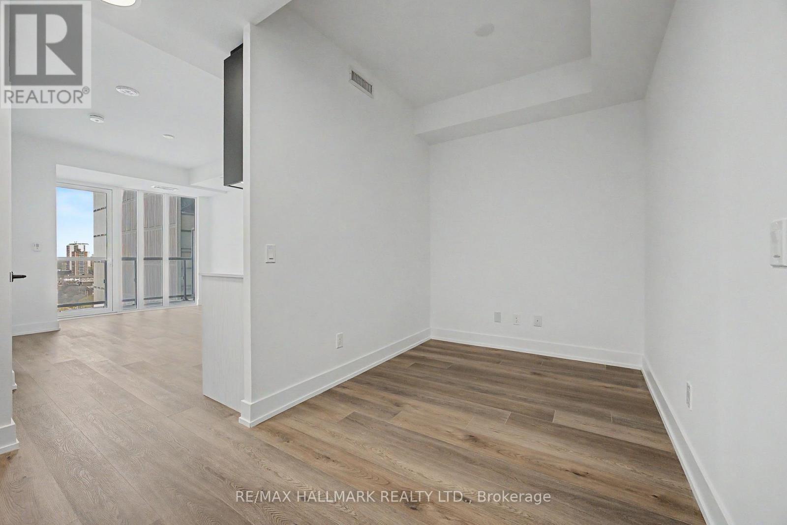 A spacious room with wooden flooring and white walls.