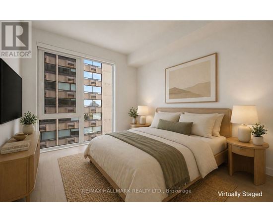 A bedroom with a large bed, a nightstand, and a window with a view of a building.