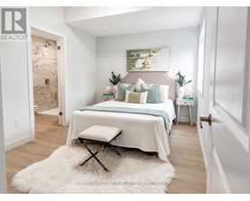 A bedroom with a bed, a bench, and a painting on the wall.