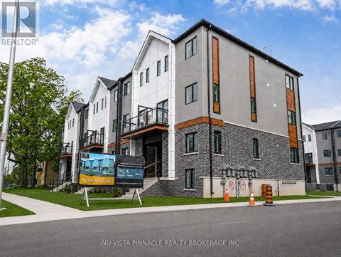 A modern building with a sign that says "Now Renting" in front of it.