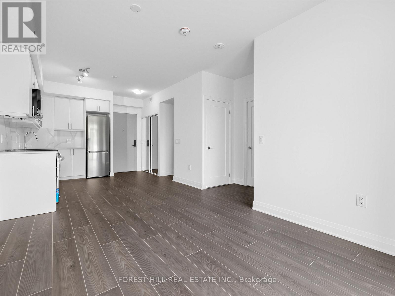 A spacious room with wood flooring and white walls.