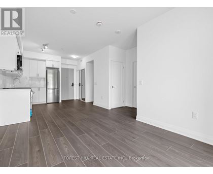A spacious room with wood flooring and white walls.