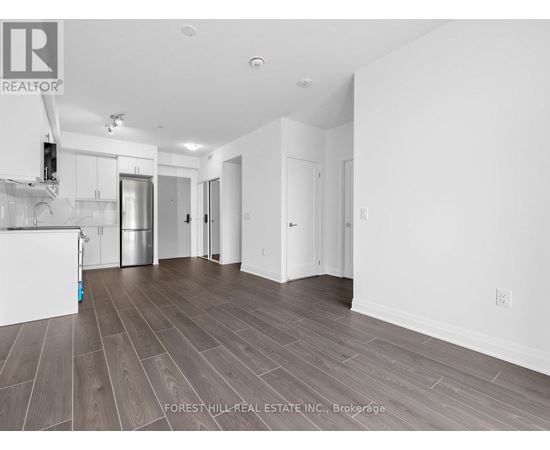 A spacious room with wood flooring and white walls.