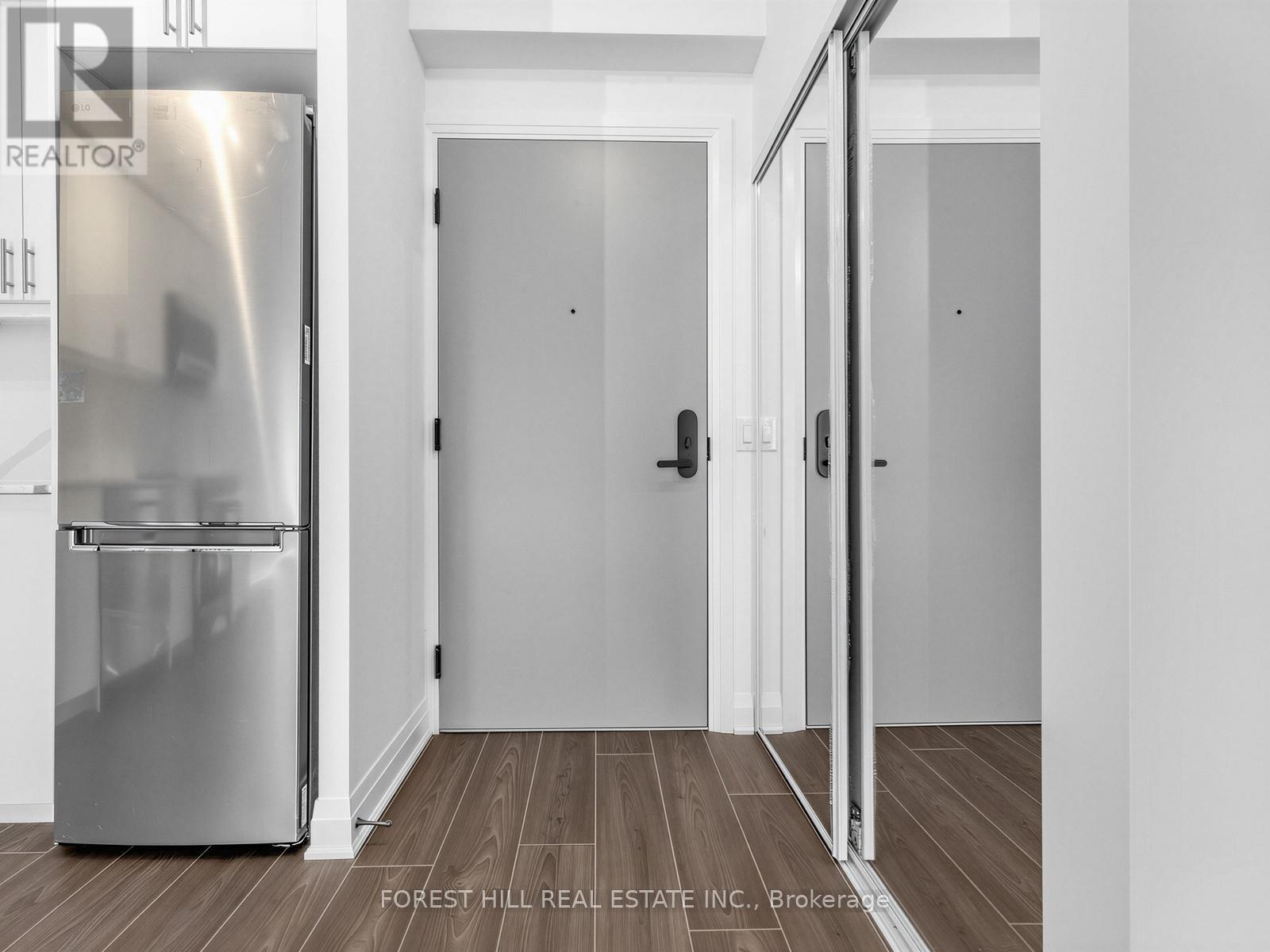 A stainless steel refrigerator in a kitchen with white walls and wooden flooring.