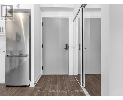 A stainless steel refrigerator in a kitchen with white walls and wooden flooring.